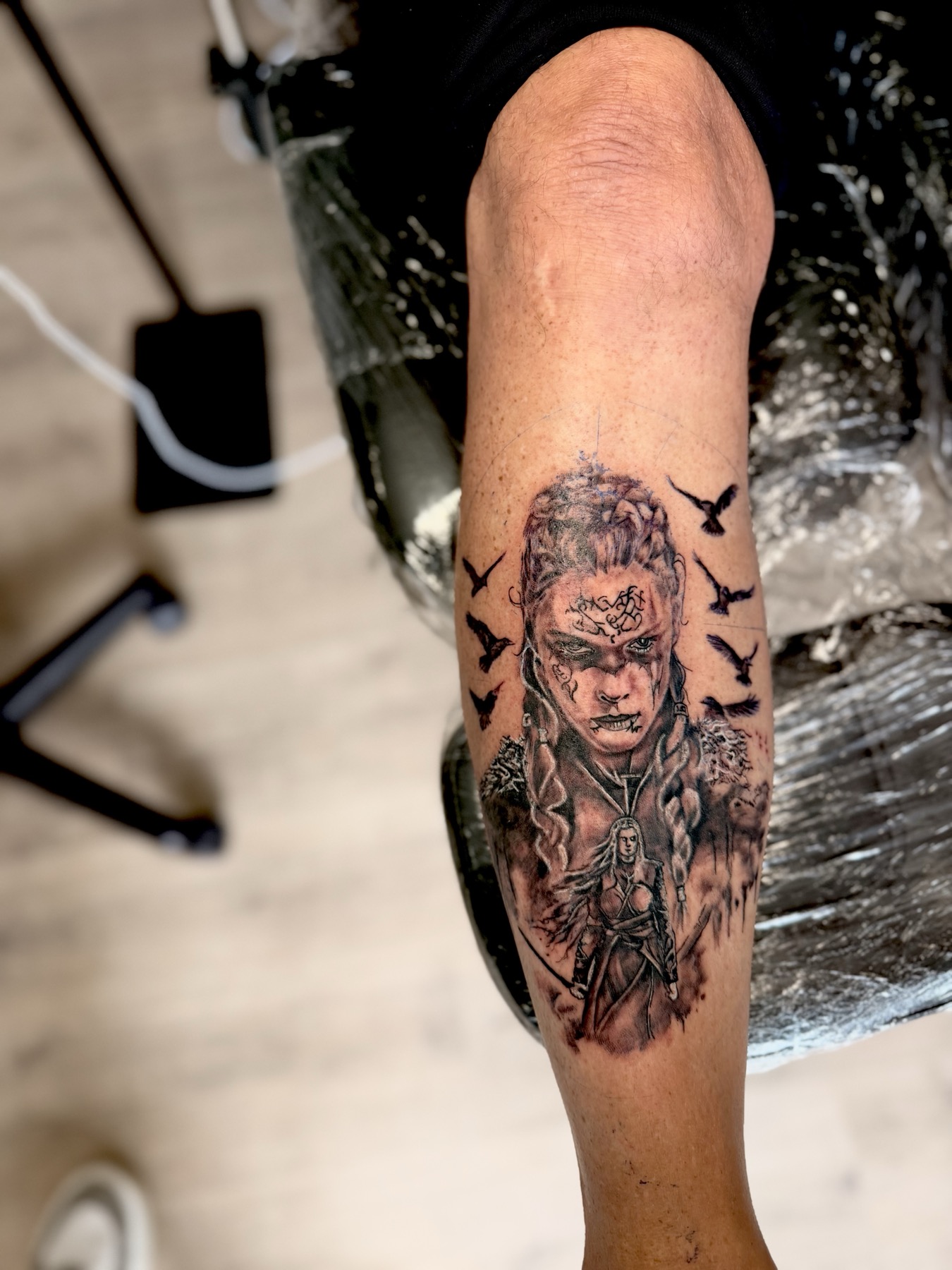 Black and grey tattoo of a warrior queen with ravens on a calf